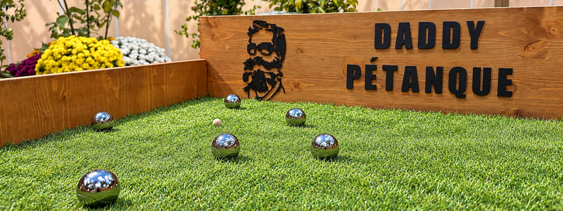 Mini-boules, cochonnet et signature Daddy Pétanque sur le gazon